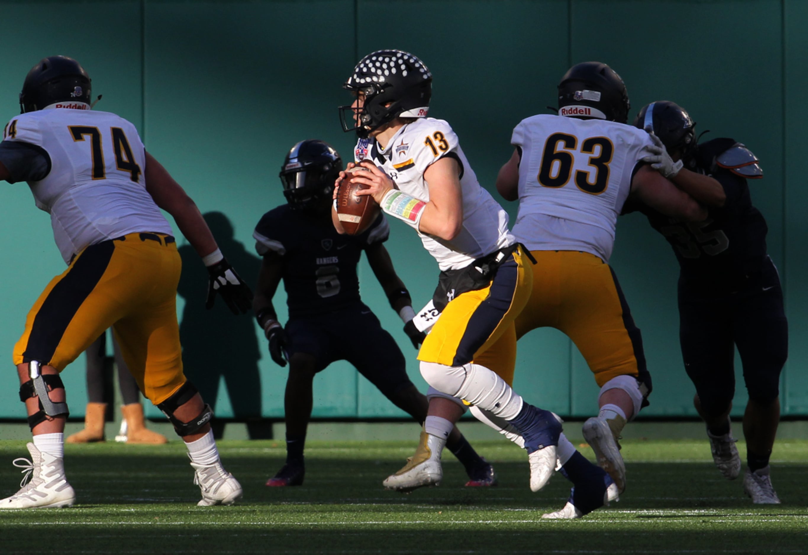 Highland Park quarterback Brayden Schager (13) rolls out behind the protection of his...
