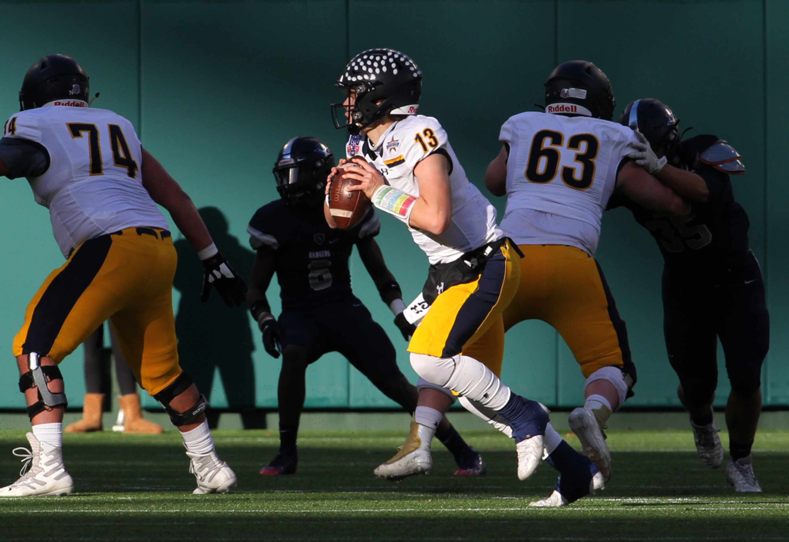 Highland Park quarterback Brayden Schager (13) rolls out behind the protection of his...