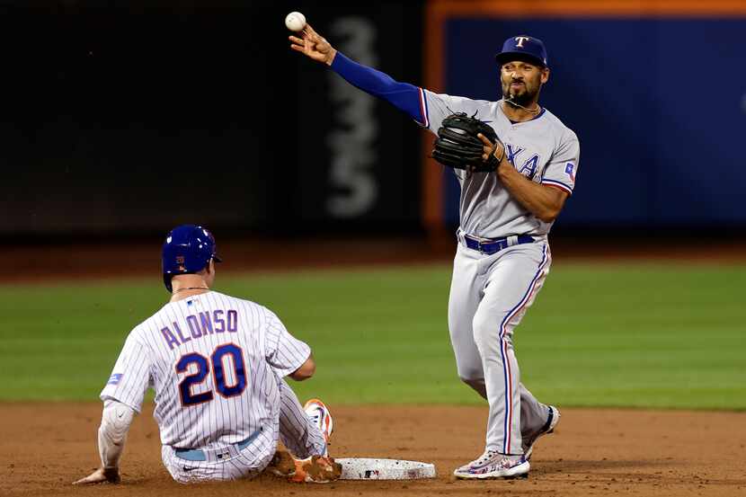 Texas Rangers second baseman Marcus Semien throws to first after forcing out New York Mets'...
