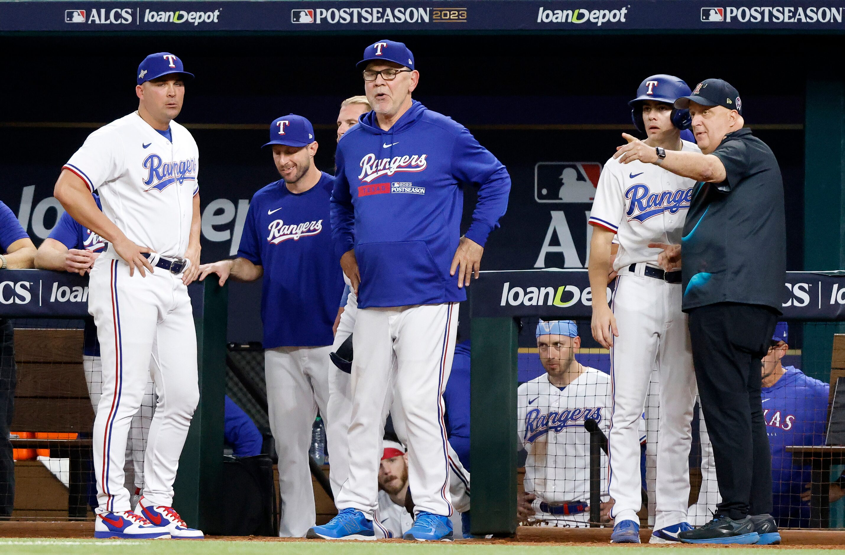 Texas Rangers manager Bruce Bochy (center) waits for the umpires to confer and eventually...