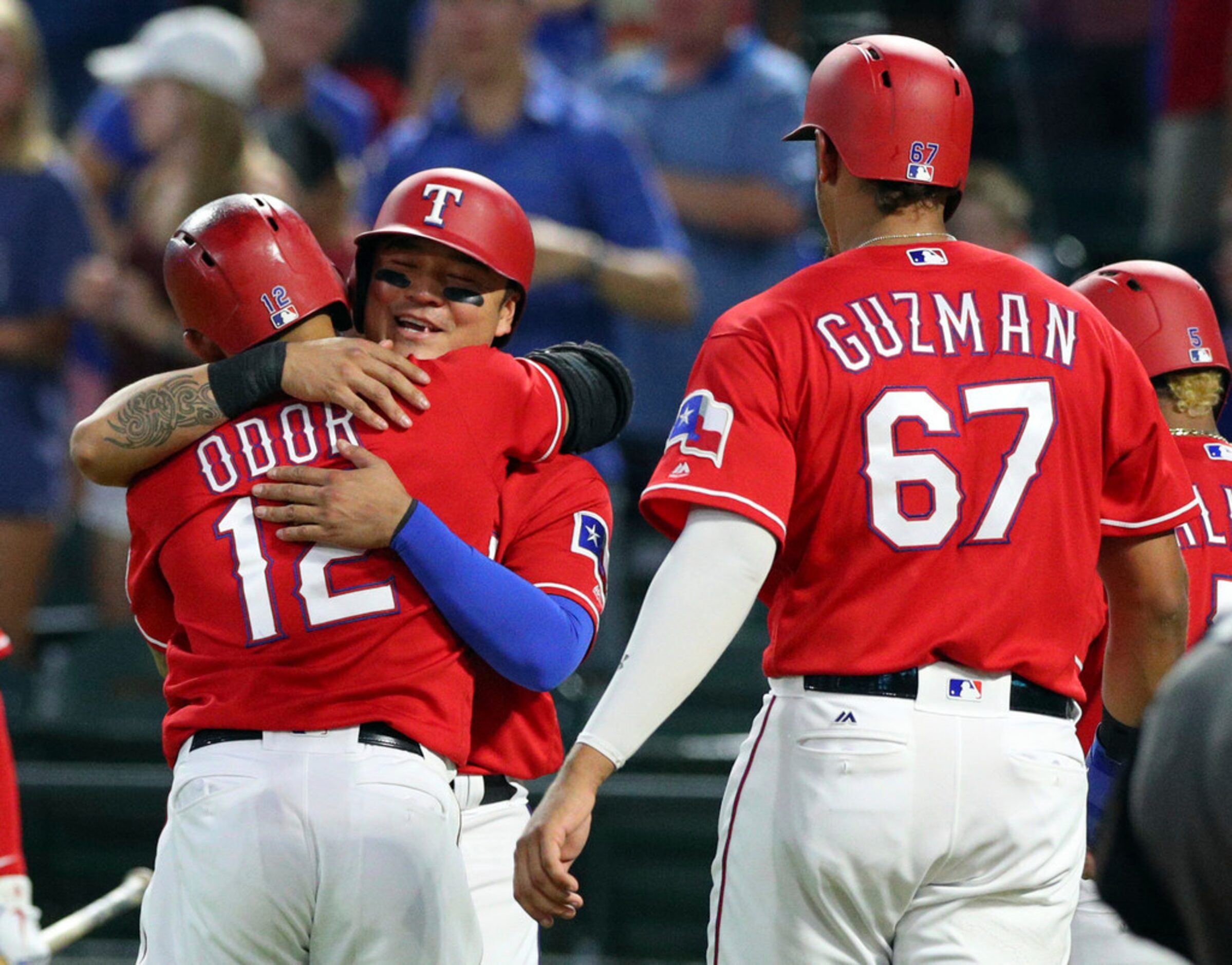 Texas Rangers' Rougned Odor (12) gets a hug from Shin-Soo Choo (17), who scored along with...