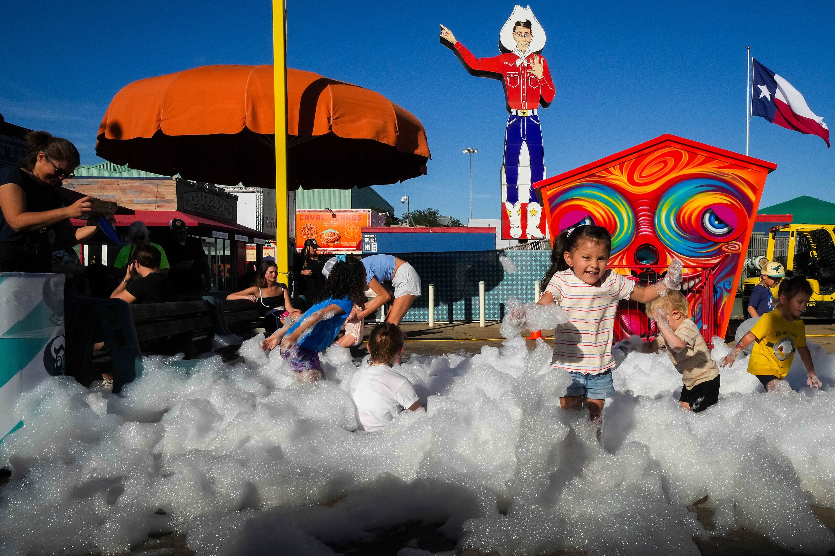 Children play in soap bubble outside the Bubble House fun house on the midway at the State...