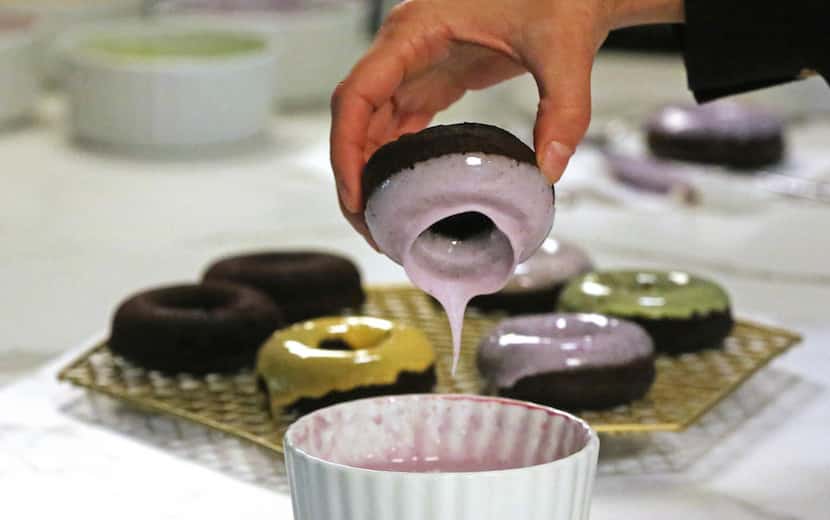 Kristen Massad dips a homemade doughnut into a glaze made of milk, powdered sugar and...