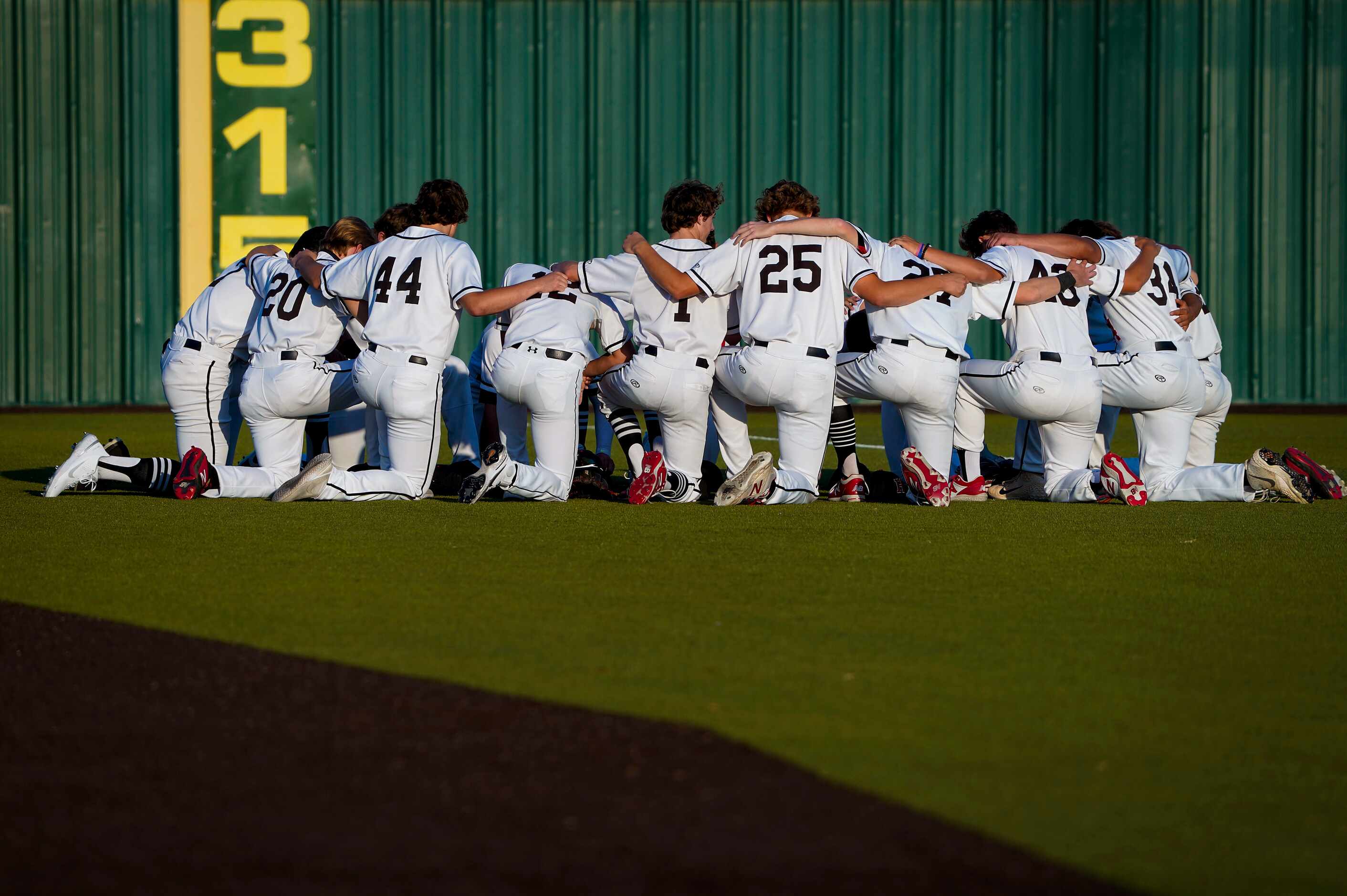 Rockwall-Heath players take a knee in the outfield before a district 10-6A high school...
