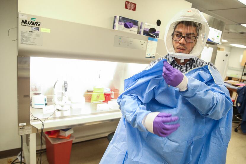 Juan Jaramillo, an arbovirus technologist, dons protective equipment during a mosquito lab...