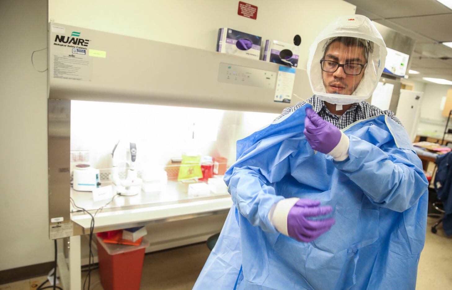 Juan Jaramillo, an arbovirus technologist, dons protective equipment during a mosquito lab...