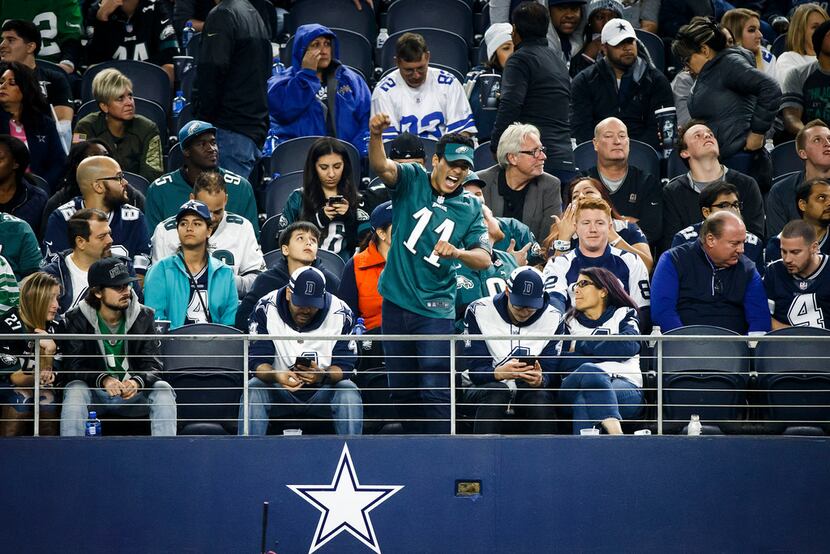 Surrounded by somber Dallas Cowboys fans, a Philadelphia Eagles fan celebrates during the...