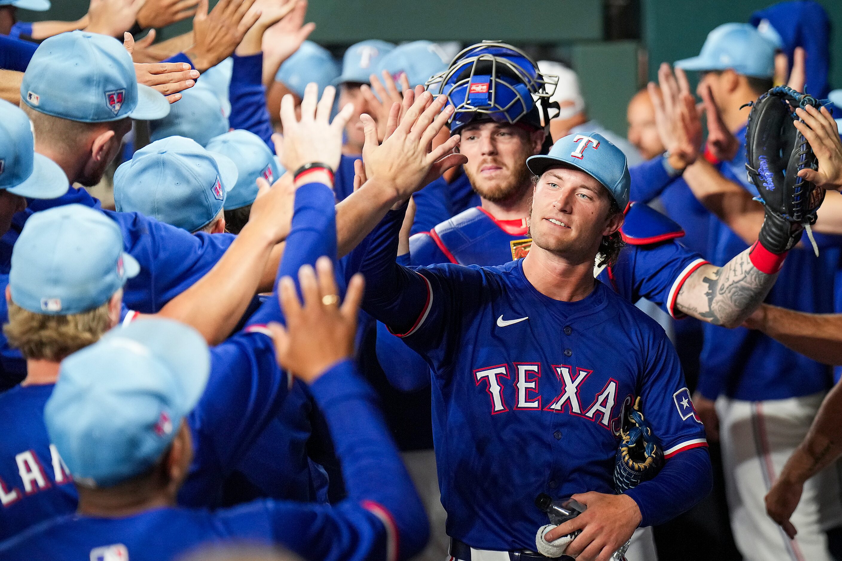 Texas Rangers pitcher Jake Latz high fives teammates before an exhibition baseball game...