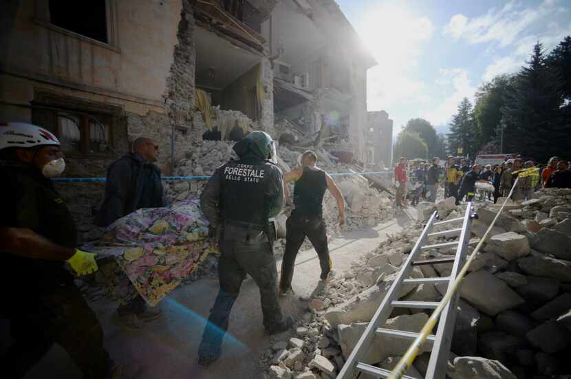 Rescuers carry the body of an earthquake victim next  in Amatrice. Scores of buildings were...
