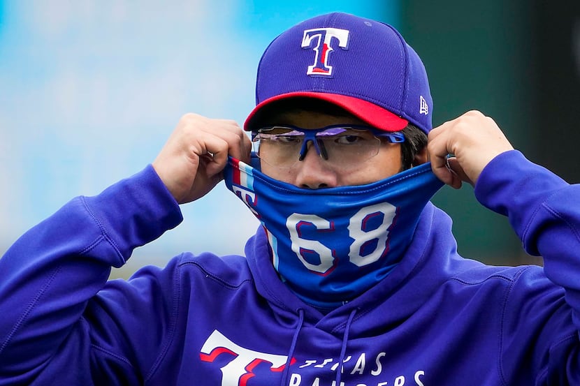 Texas Rangers pitcher Hyeon-jong Yang adjusts his face covering before of a spring training...