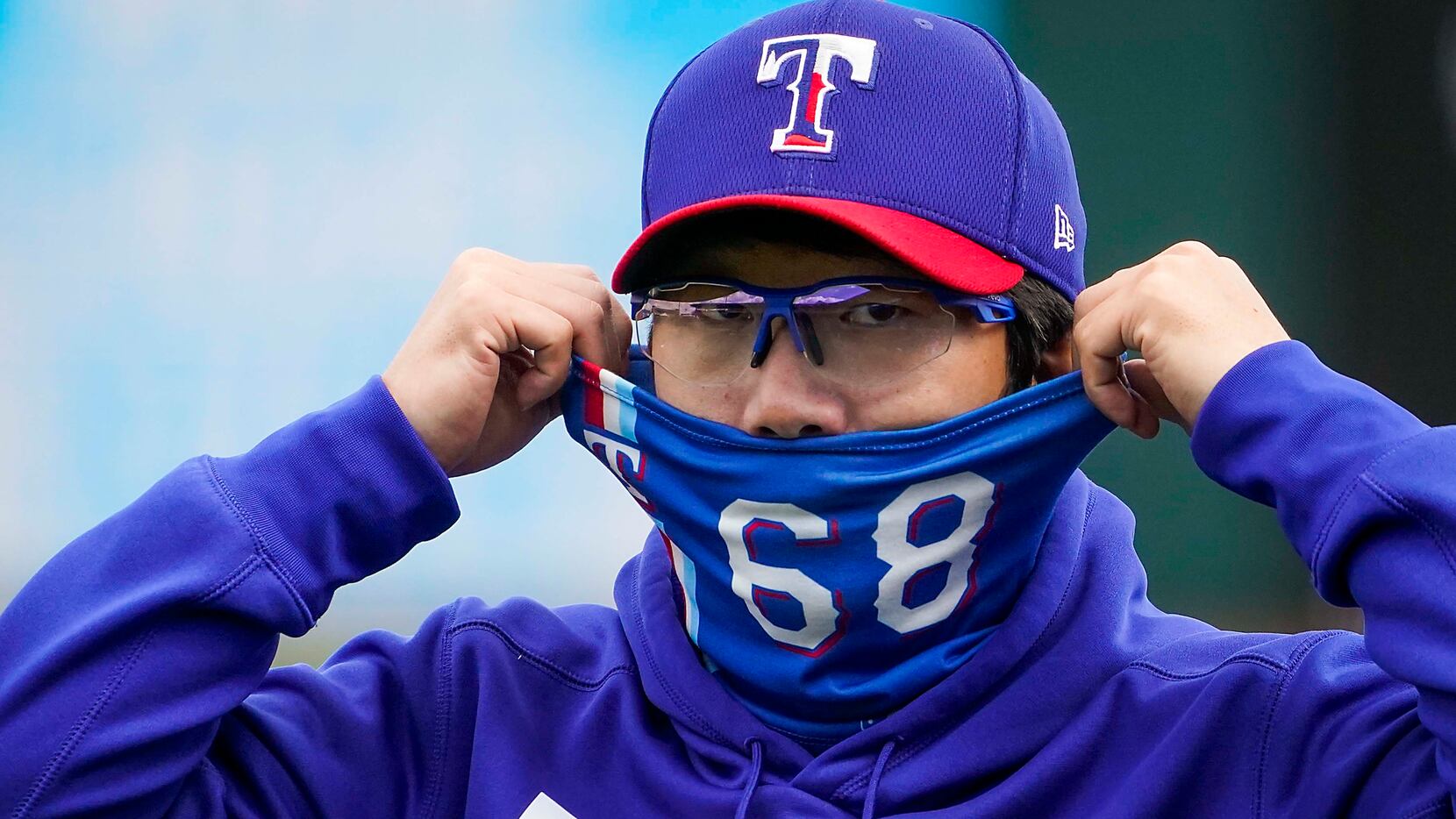 Texas Rangers pitcher Hyeon-jong Yang adjusts his face covering before of a spring training...