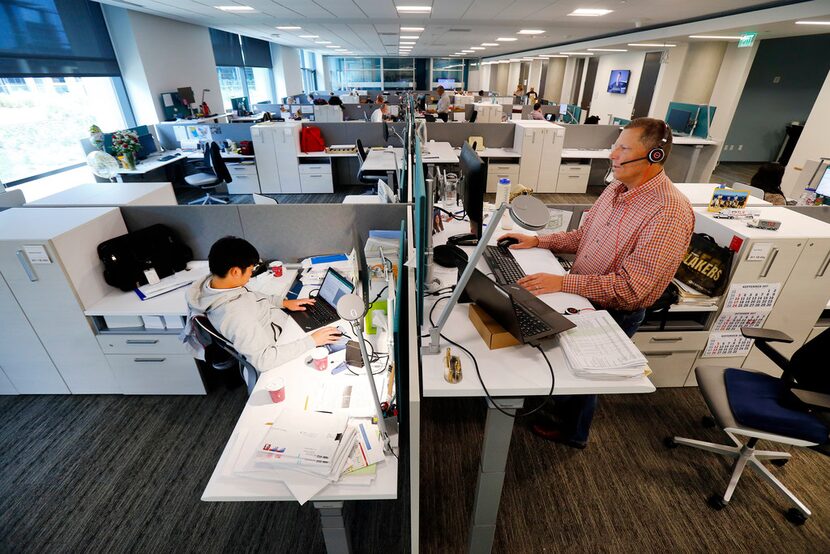 Foshifumi Suzumi (left) and Scott Heimer work across the desk from one another in an open...