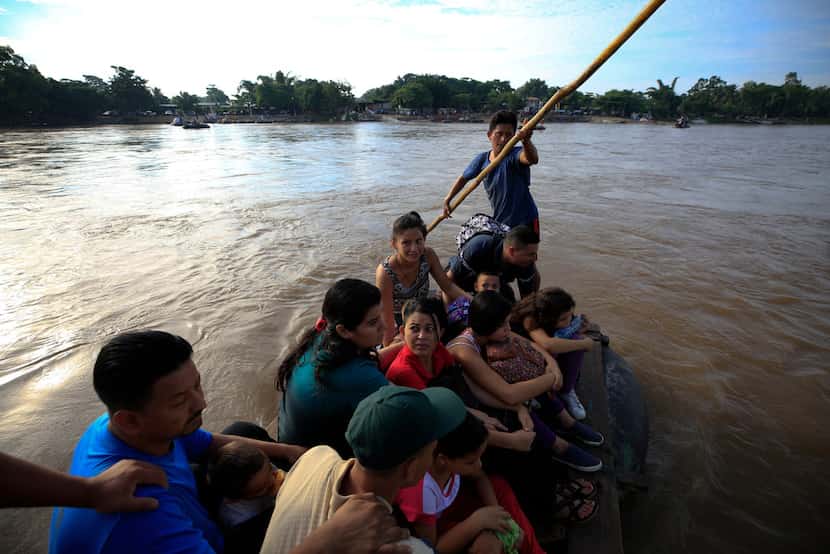 A group of more than a dozen Honduran migrants ride a raft across the Suchiate river after...