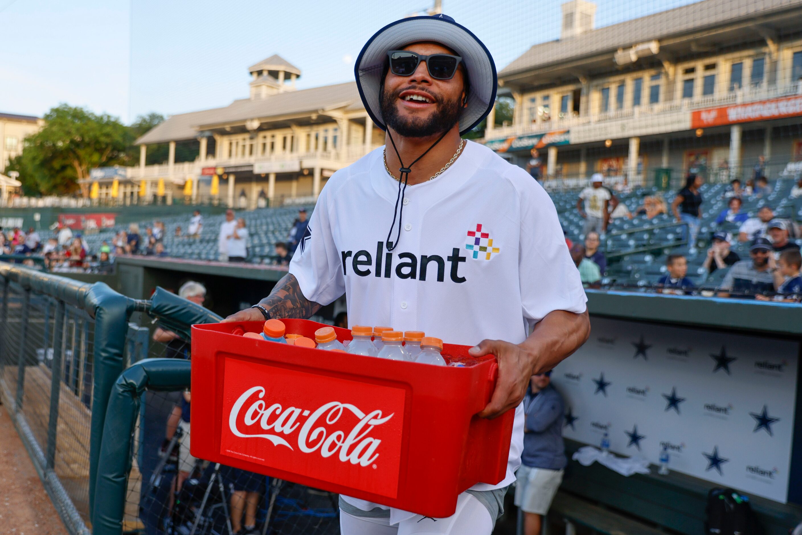 Dallas Cowboys QB Dak Prescott walks out of the dugout carrying a case full of drinks during...