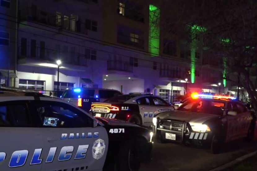 Dallas police squad cars park outside an apartment complex where a man was shot to death...