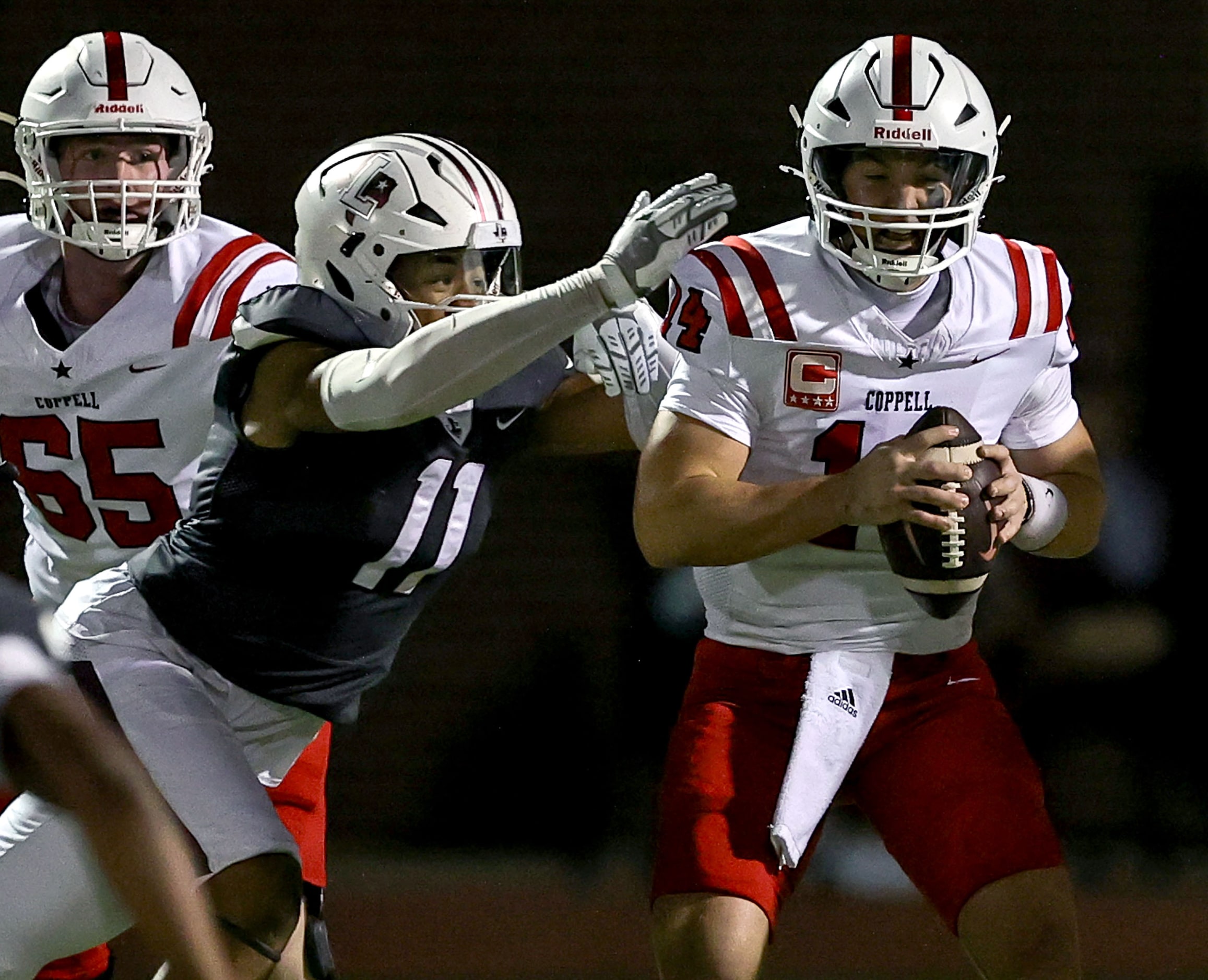 Coppell quarterback Edward Griffin (14) gets pressured by Lewisville defensive lineman Rhyan...