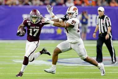 Texas A&M wide receiver Ainias Smith (17) fends off Oklahoma State defensive end Trace Ford...