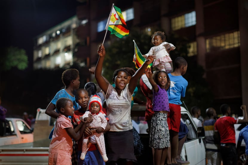 Zimbabweans celebrate at night at an intersection in downtown Harare, Zimbabwe Tuesday, Nov....