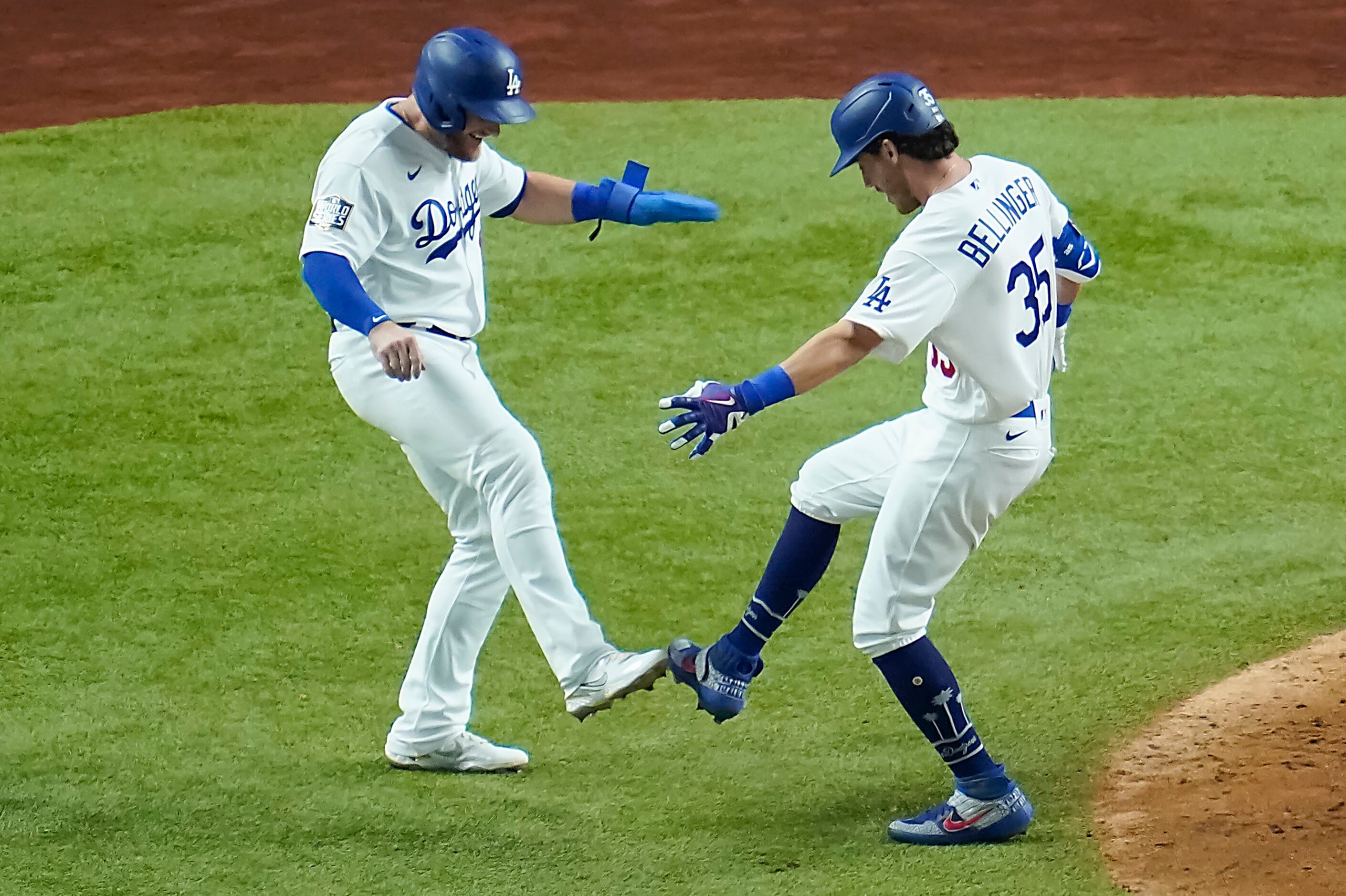 Los Angeles Dodgers center fielder Cody Bellinger taps toes with first baseman Max Muncy as...