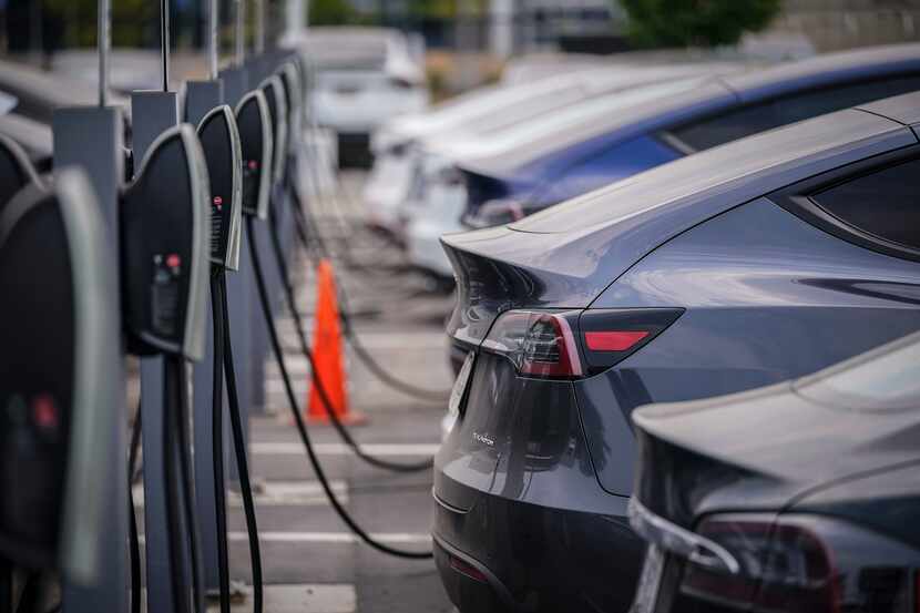 FILE - A group of Tesla cars line up at charging stations at a dealership in Littleton,...