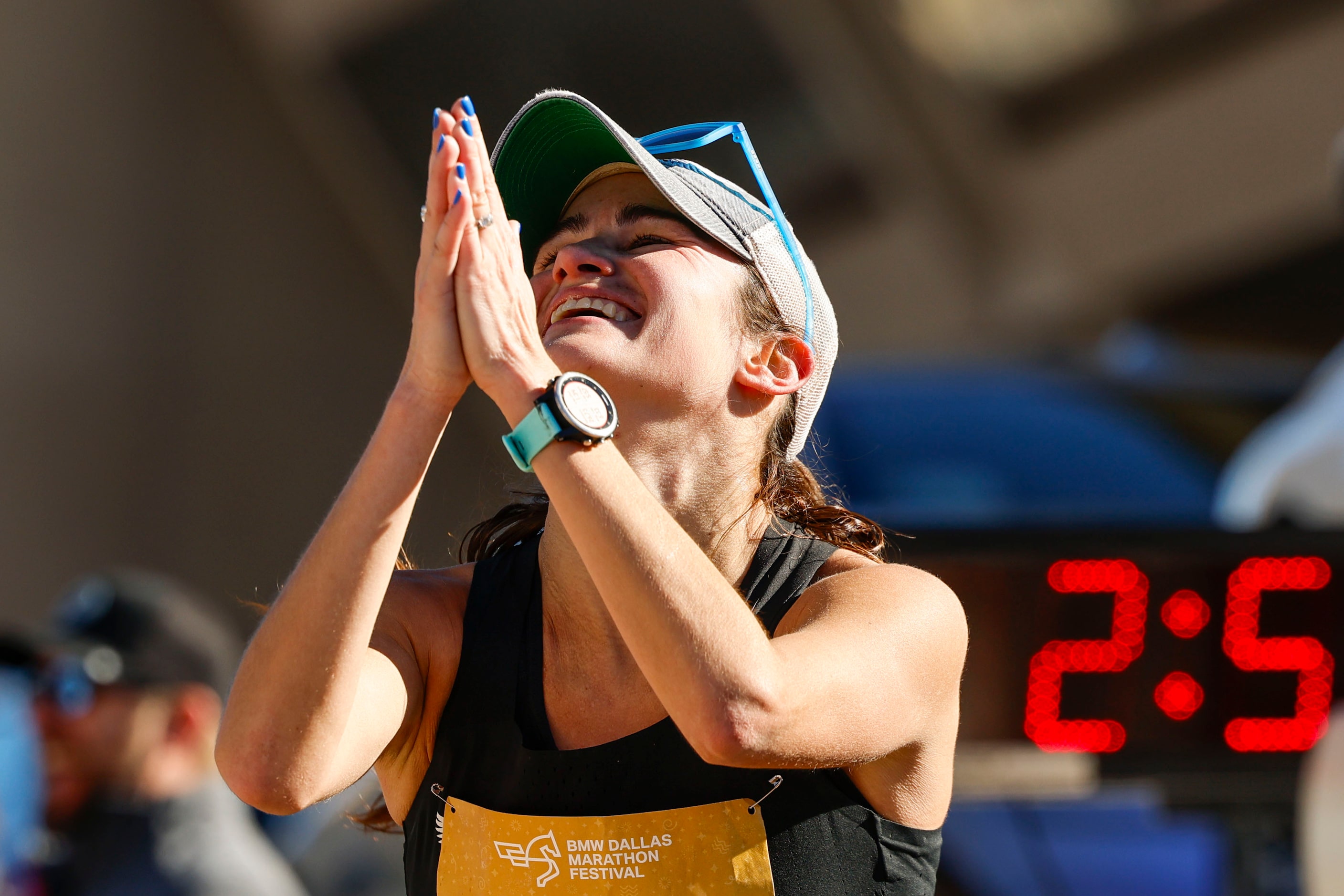 Women’s marathon finisher Jill Wolf, of Dallas, celebrates after reaching the finish line...