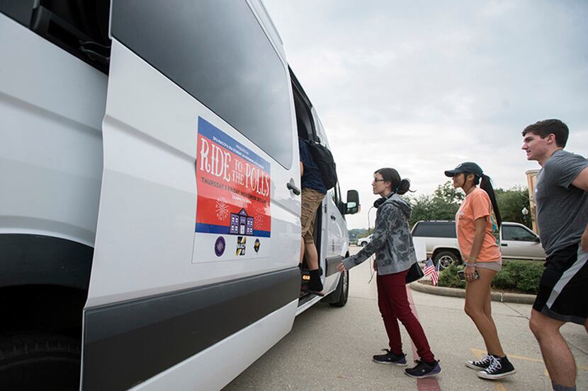 Young voters file onto a shuttle provided by Stephen F. Austin State University's Student...
