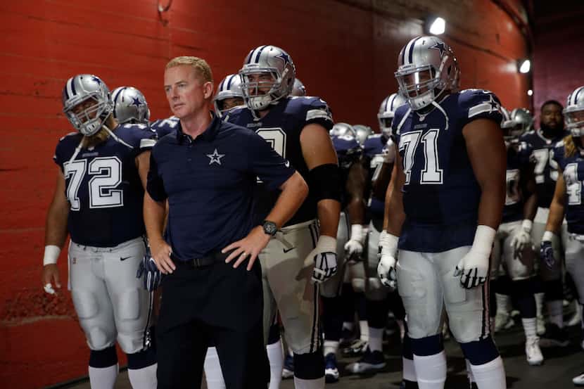 Dallas Cowboys head coach Jason Garrett, center, leads his team in a tunnel playing the Los...