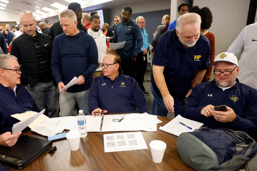 Highland Park’s staff, including head coach Randy Allen (seated, center) huddle following...