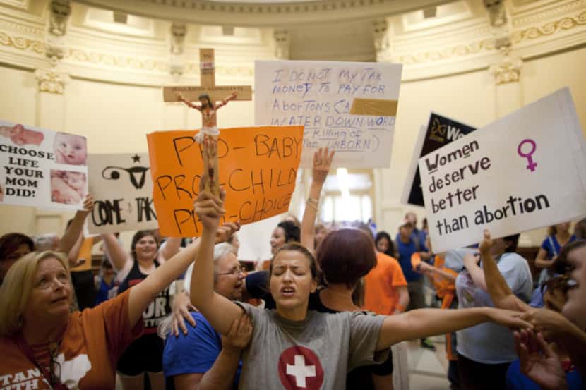 Abortion protester Katherine Aguilar held a crucifix and prayed as demonstrators on both...