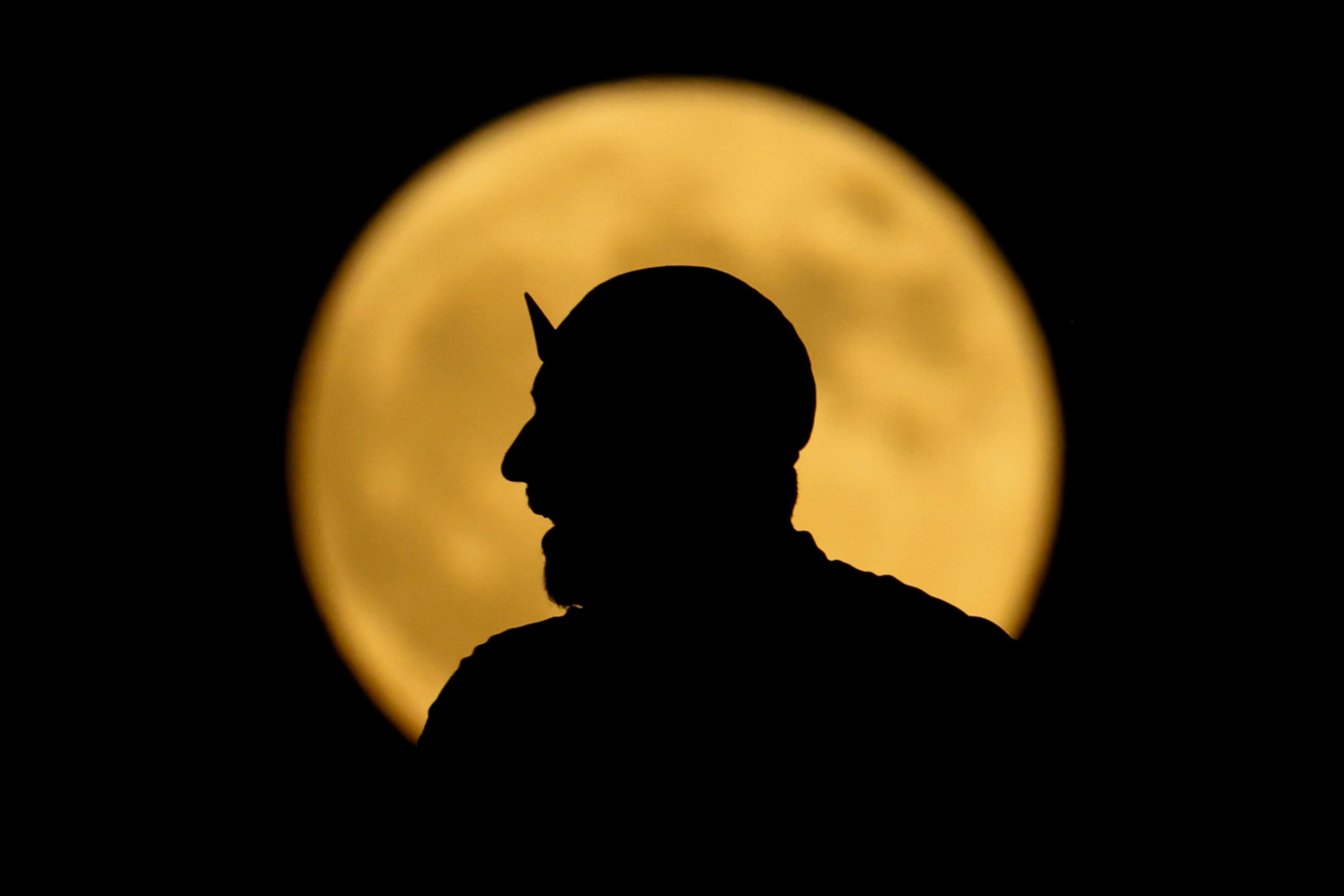 A person is silhouetted against the rising full super harvest moon, on Tuesday, Sept. 17,...