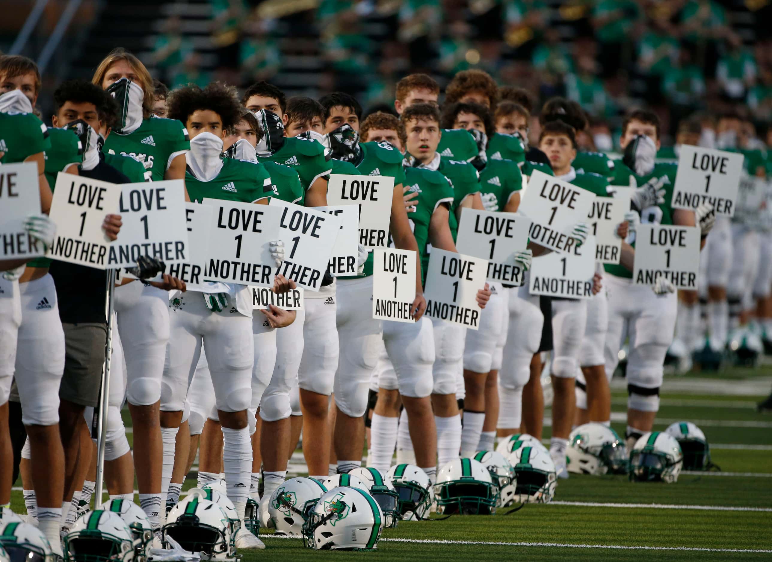 Southlake Carroll players show unity during the nation anthem during their high school...