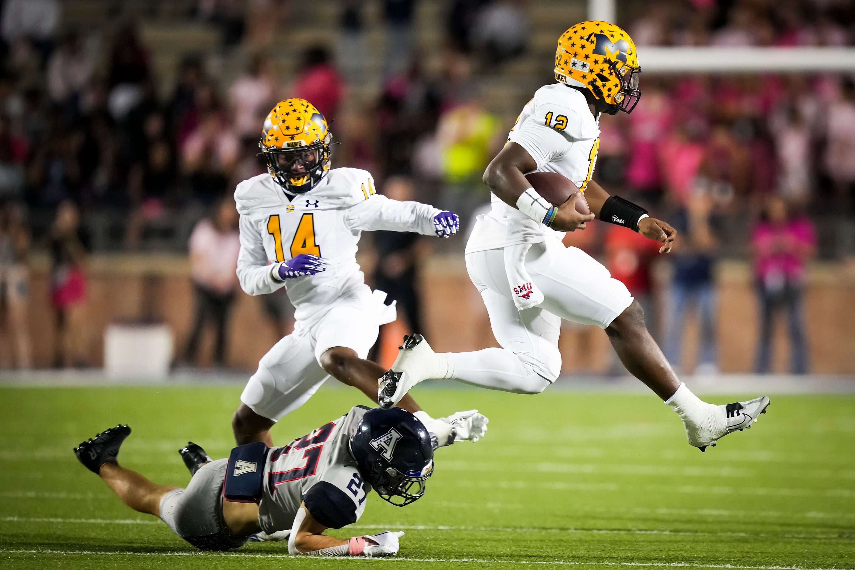 McKinney quarterback Keldric Luster (12) leaps over Allen defensive back Emery Lasseter (27)...