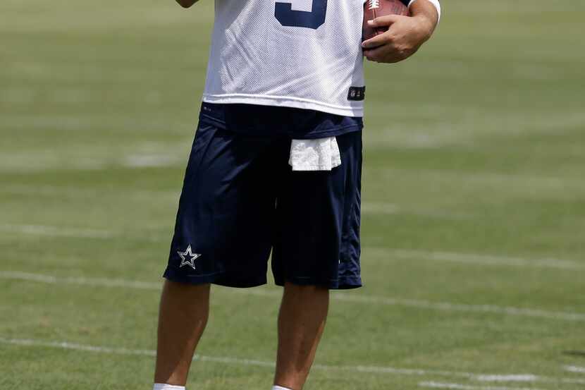 Dallas Cowboys quarterback Tony Romo watches as the team runs drills during an NFL football...