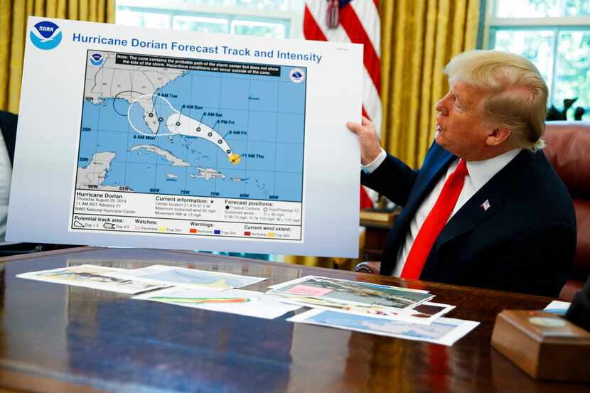 El presidente Donald Trump sostiene un mapa mientras hace declaraciones a la prensa después...