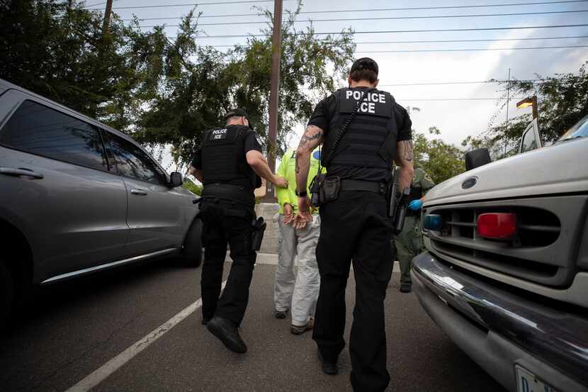  U.S. Immigration and Customs Enforcement (ICE) officers escorted a man in handcuffs during...