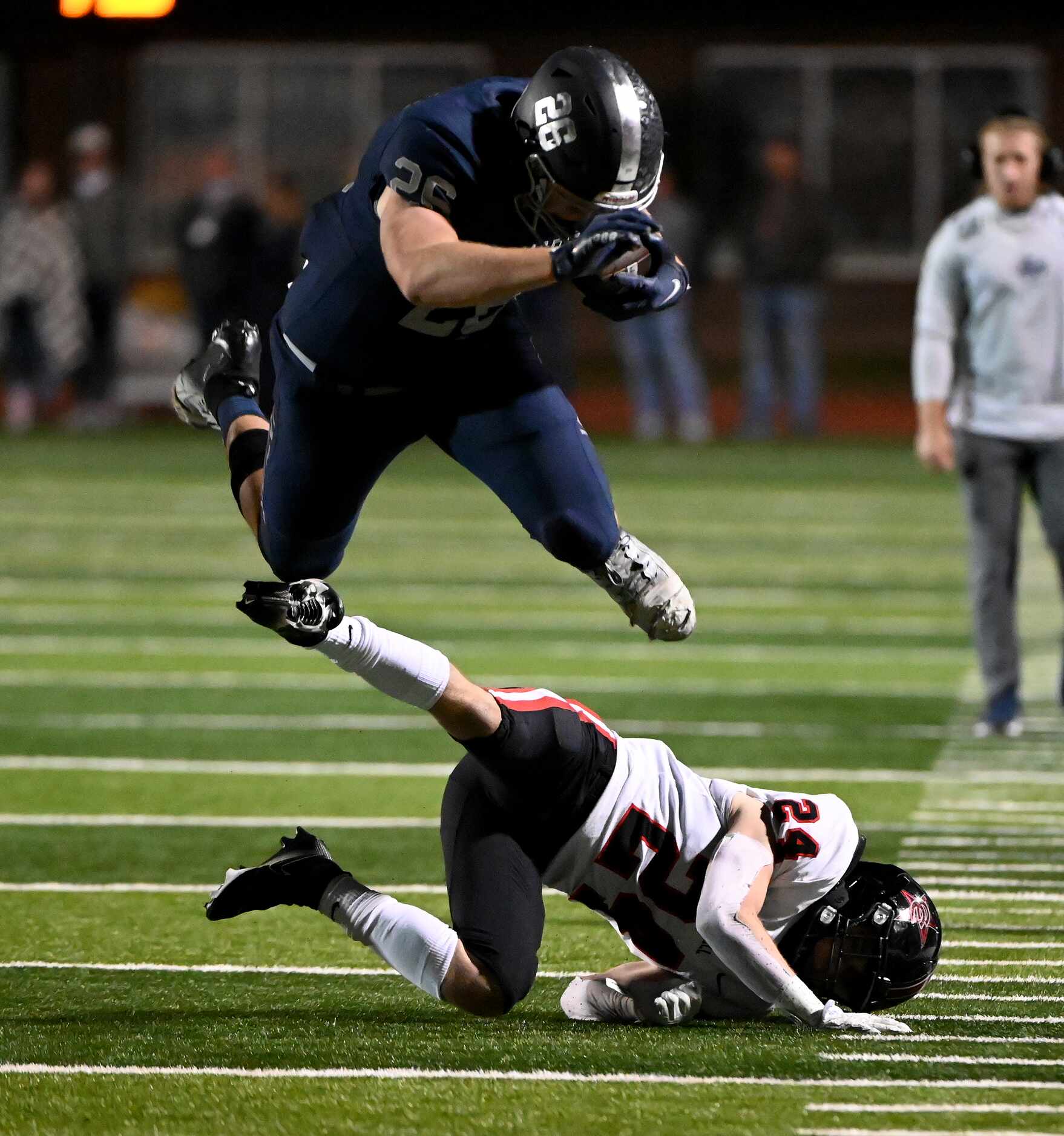 Flower Mound's Caden Jensen (26) leaps over a tackle attempt by Coppell's free safety...