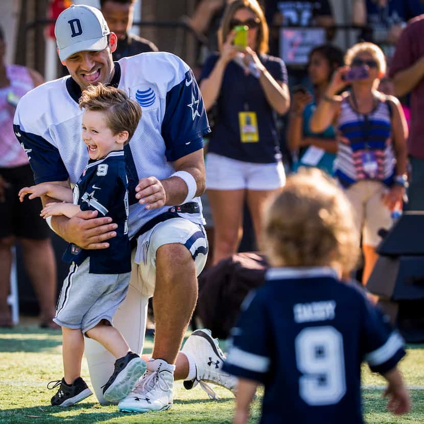 Dallas Cowboys quarterback Tony Romo hugs his son Hawkins, 3, as younger son Rivers, 1, runs...