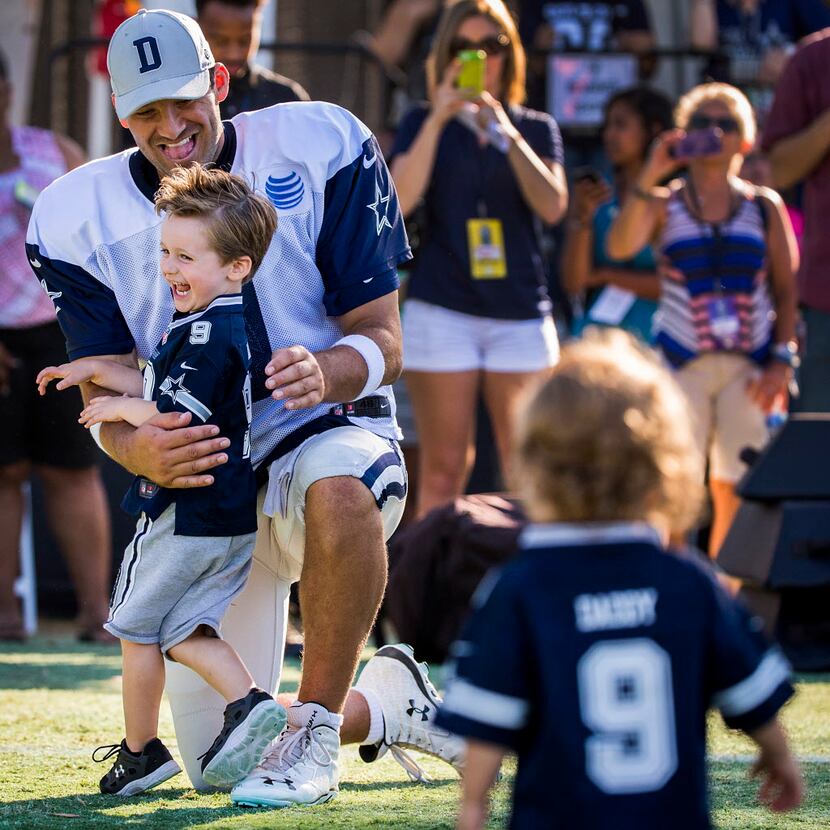 Dallas Cowboys quarterback Tony Romo hugs his son Hawkins, 3, as younger son Rivers, 1, runs...