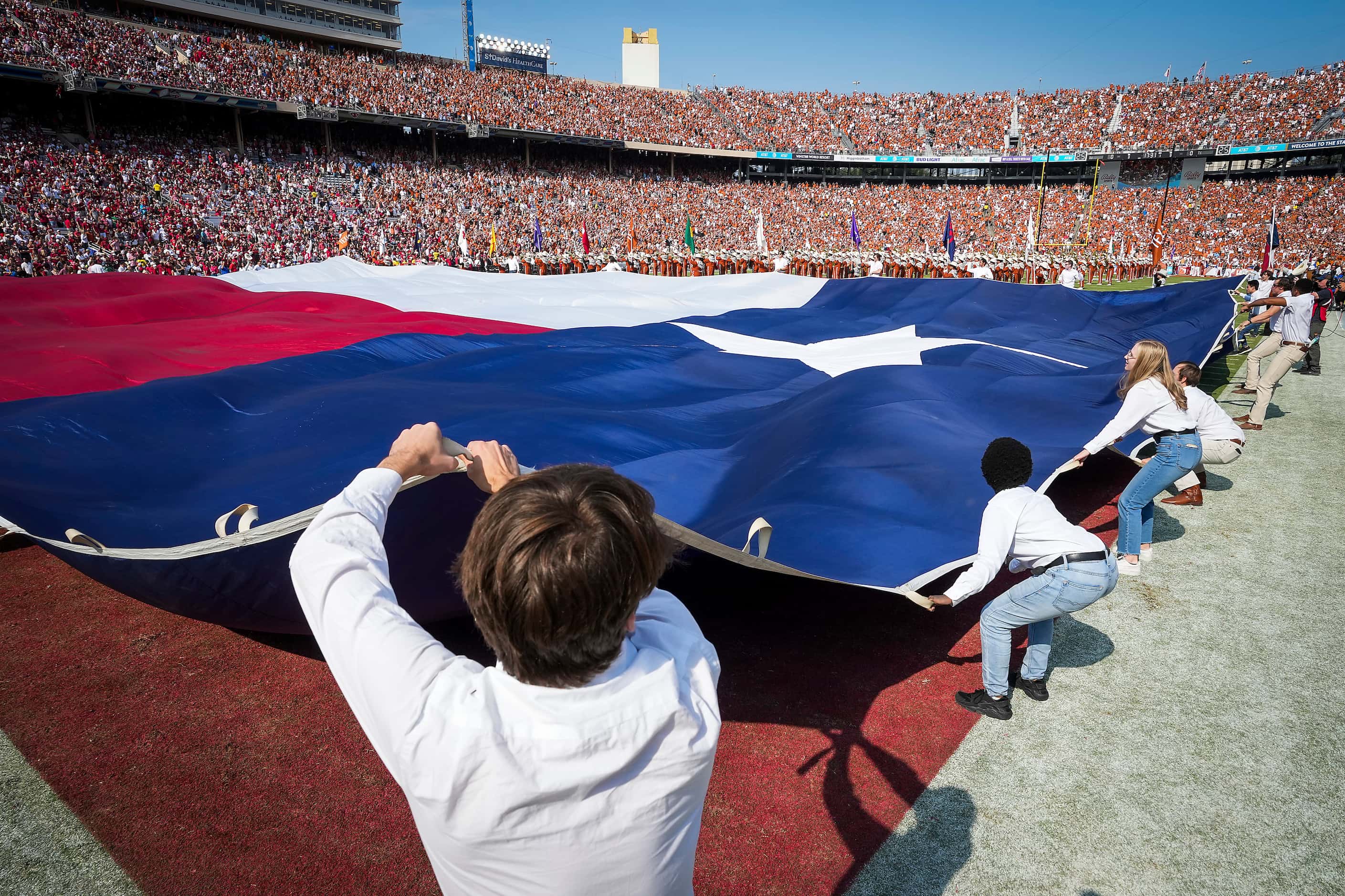 A large Texas flag covers the end zone before the annual Red River Showdown football game...