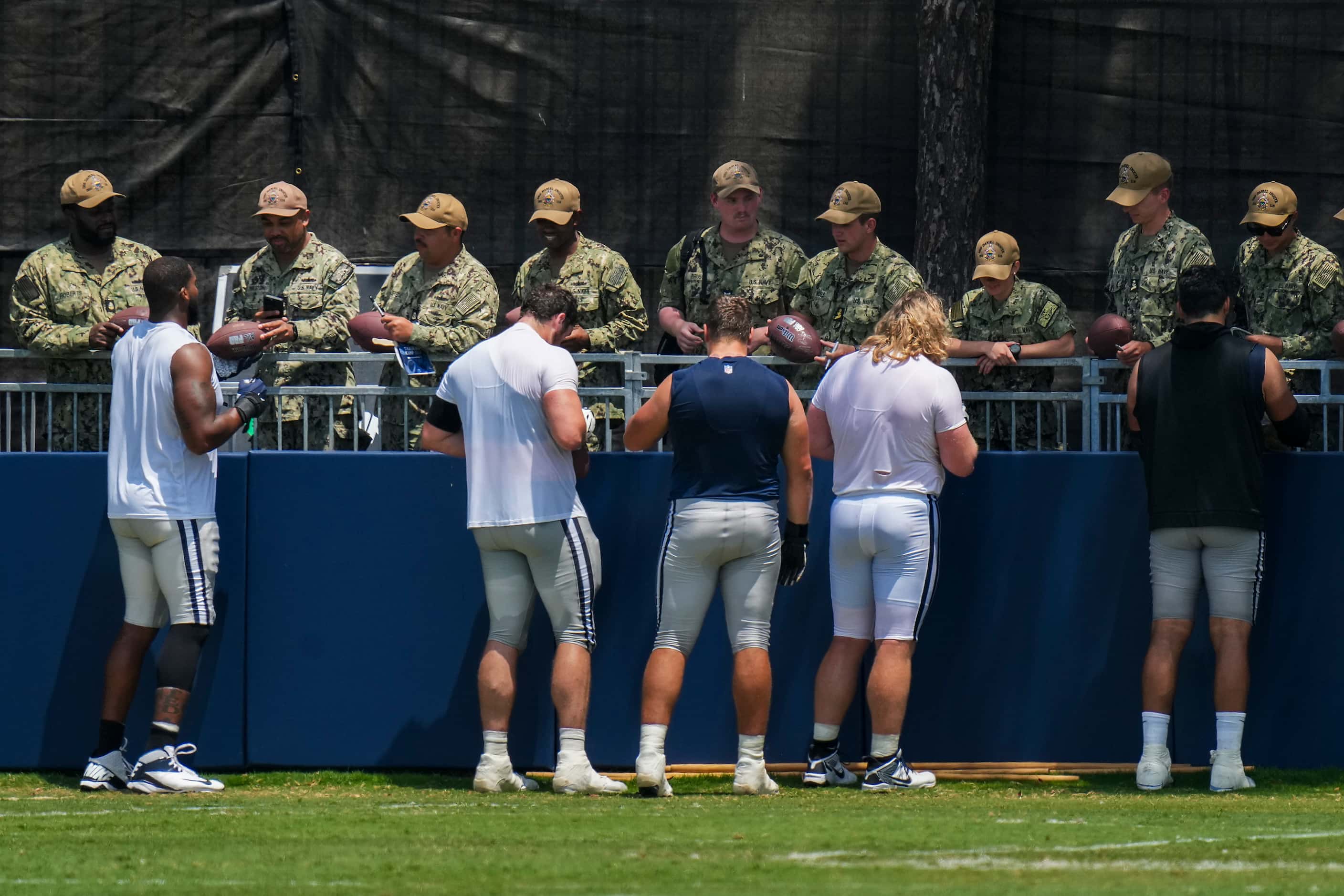 Dallas Cowboys players sign autographs for service members following a training camp...