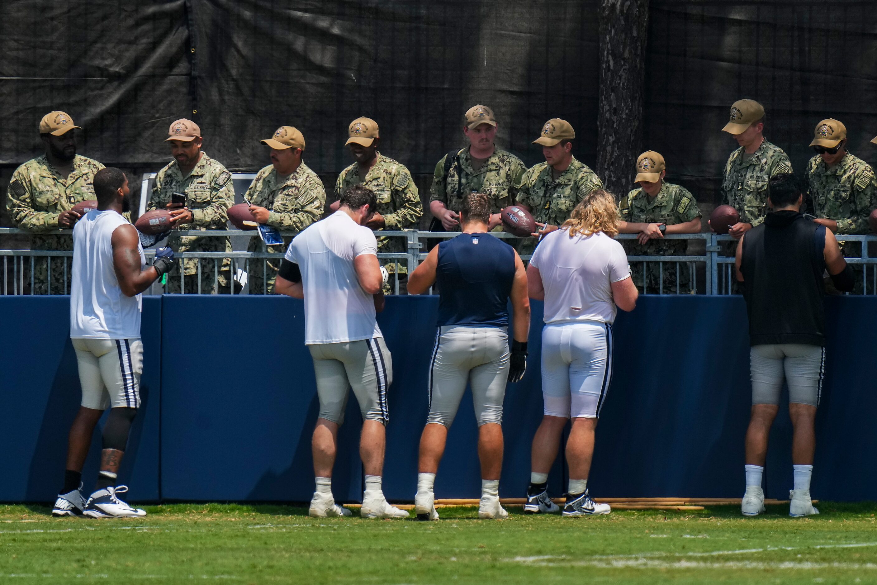 Dallas Cowboys players sign autographs for service members following a training camp...