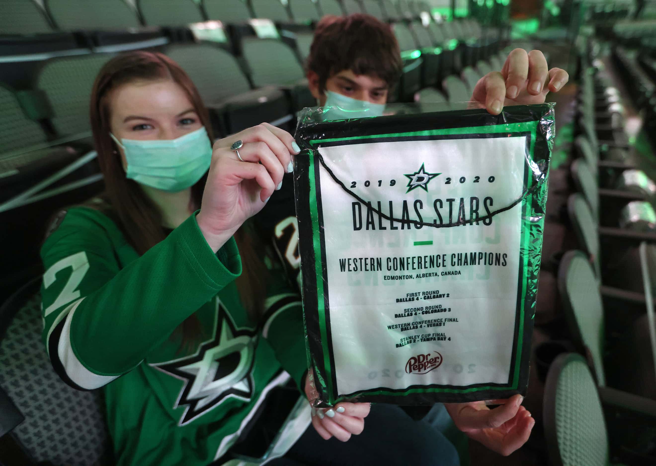 Kendra Maher and Daniel Mignault of Dallas hold up one of the replica banners given to fans...