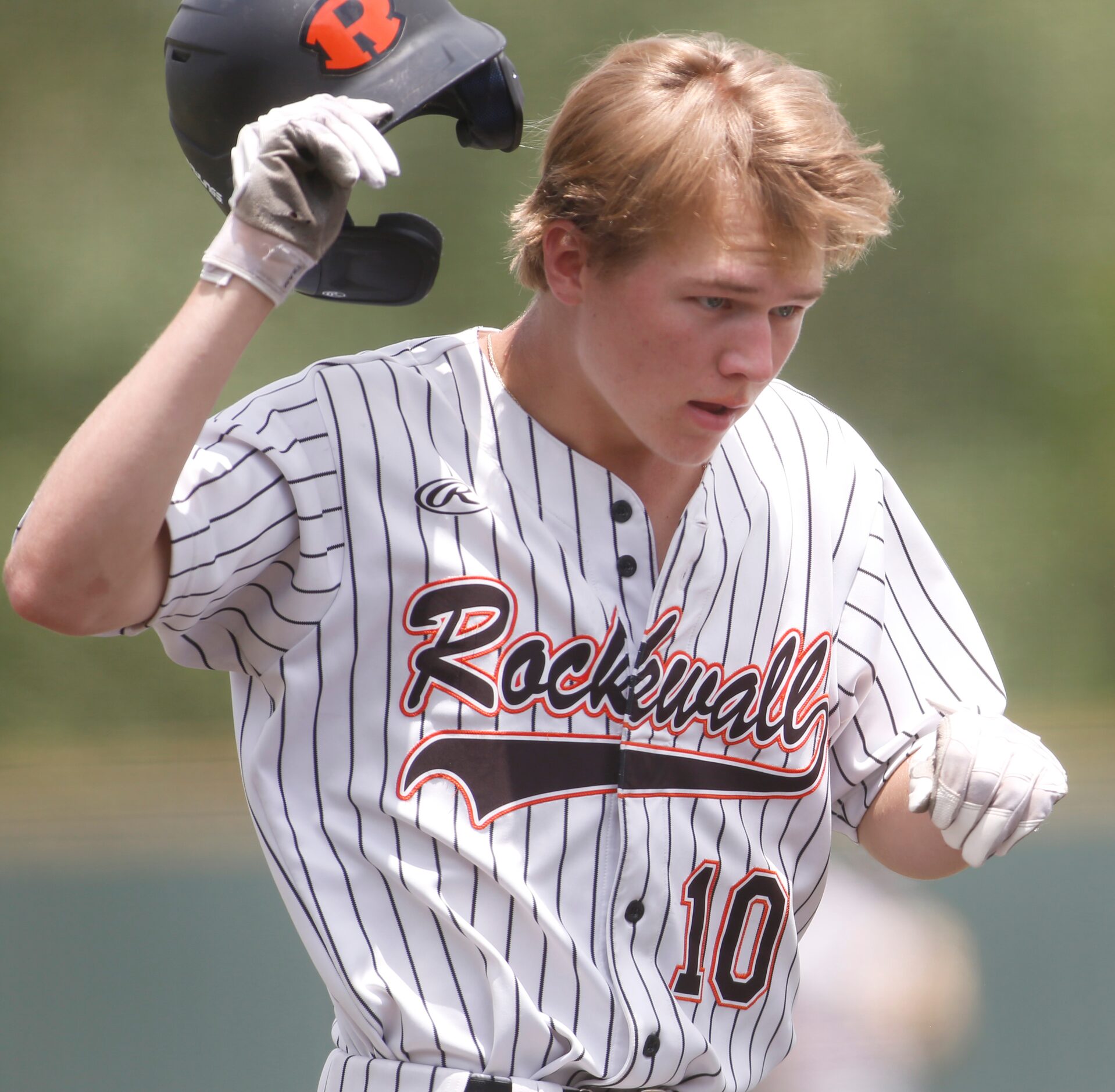 Rockwall outfielder Barrett Riebock (10) removes his helmet just before reaching home plate...