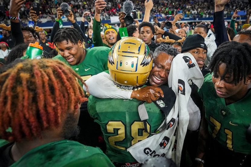 DeSoto head coach Claude Mathis hugs defensive back Caden Mathis (28) as he celebrates with...