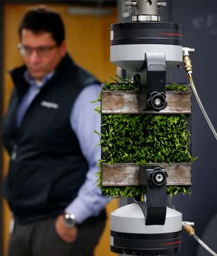 Shaw Sports Turf director of research and innovation Philipe Aldahir watches as a piece of...