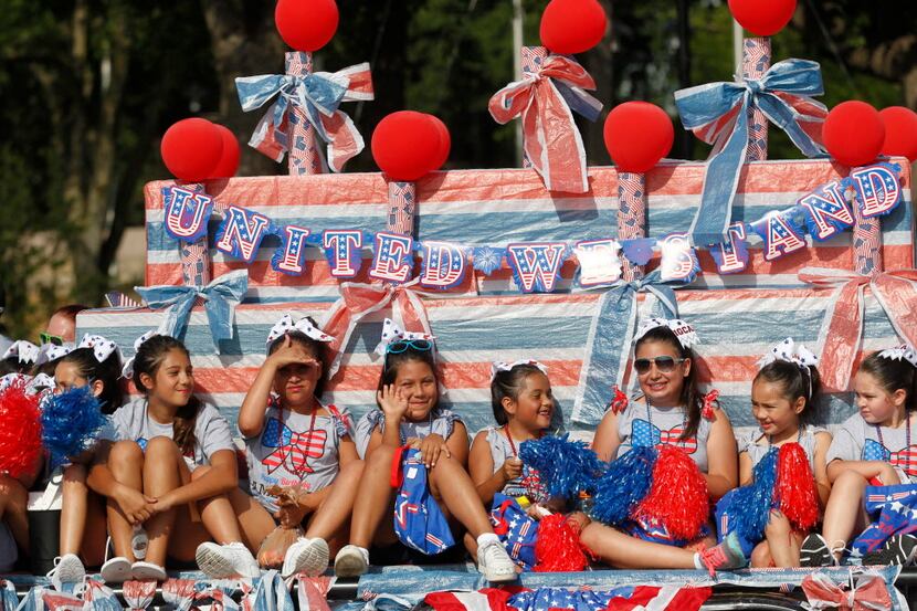 Members of the Irving Girls Cheerleading Association ride a float during a past 4th of July...