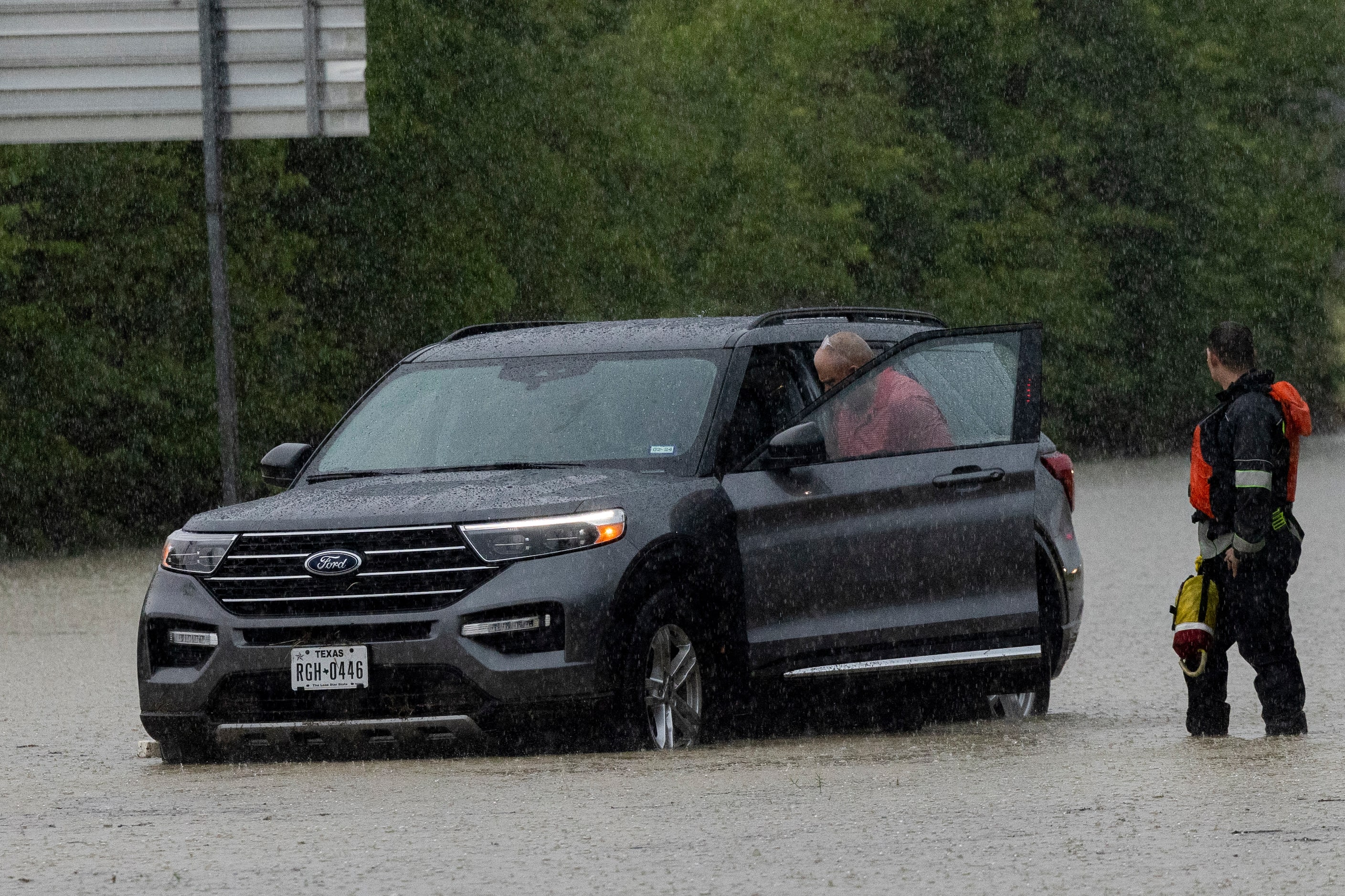 A member of the Mesquite Fire Department helps a motorist check his car on the flooded...