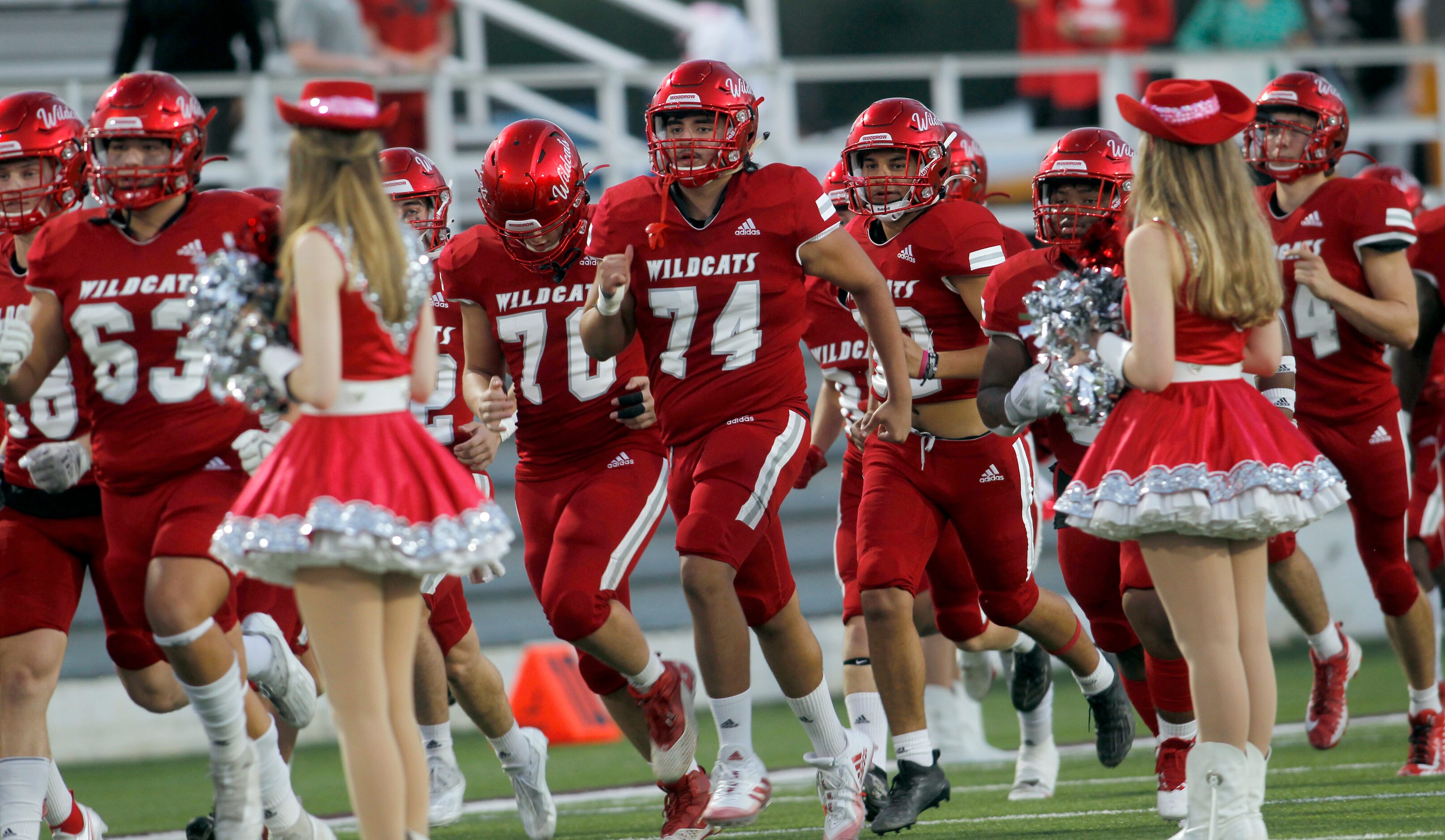 Members of the Dallas Woodrow Wilson Wildcats run onto the field before the opening kickoff...