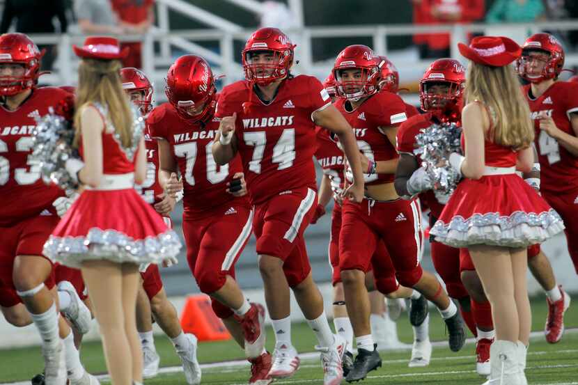 Members of the Dallas Woodrow Wilson Wildcats run onto the field before the opening kickoff...