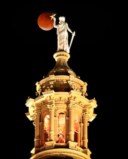 The full Super Flower Blood Moon eclipse rises over the Goddess of Liberty atop the Texas...